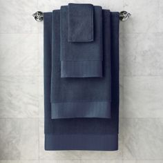 three folded towels hanging on the wall in a bathroom with marble flooring and white walls