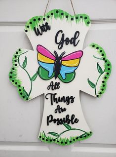 a painted cross with the words, we god all things for people on it hanging from a door