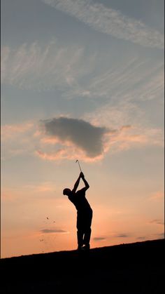 the silhouette of a man playing golf at sunset or dawn with clouds in the background