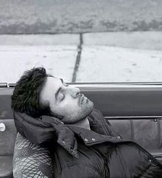 a man laying down in the back seat of a car with his head resting on someone's shoulder