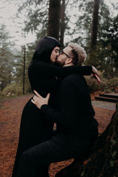 an engaged couple kissing in the woods