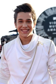 a young man wearing a white outfit smiling at the camera