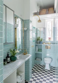 a bathroom with checkered flooring and blue tiles on the walls, along with a white toilet and sink