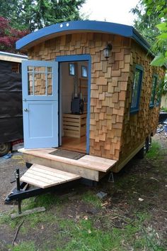 a small house made out of wood and blue doors