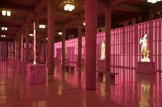 an empty room with pink lighting and statues