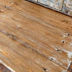 an old wooden table with peeling paint on it and some drawers in the back ground