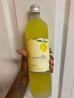 a person holding up a bottle of caravela wine in front of a door