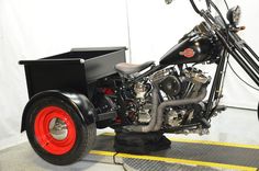 a black motorcycle with red rims parked in a garage next to a white wall