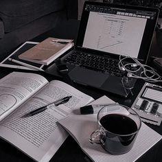 an open laptop computer sitting on top of a desk next to a cup of coffee