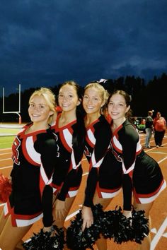 the cheerleaders are posing for a photo on the field at night with their pom poms