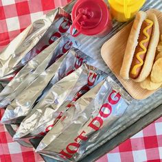 hotdogs, chips and drinks on a tray with red checkered tablecloth