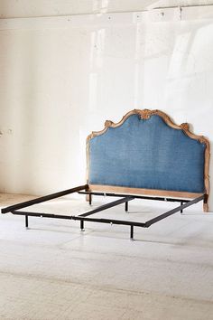 a blue bed frame sitting on top of a white floor next to an open window