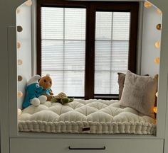 a stuffed animal sitting on top of a bed in front of a window with lights