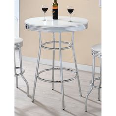 a white table with two stools and a bottle of wine