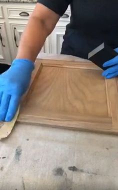 a person in blue gloves is waxing a piece of wood on a counter top