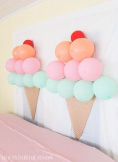 an ice cream cone filled with balloons on top of a pink table cloth covered bed