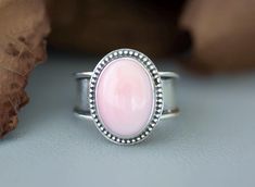 Elegant Pink Queen Conch Sterling Silver Statement Ring, perfect gift for wife, moms, girlfriend or friend. This handmade statement ring has a 18mm x 12mm oval, bezel set, cabochon that is accented with bead wire. It is mounted on a unique, tapered wide narrow band that at its widest is 1/2" then narrows to 1/8" for a comfortable fit. The holidays are right around the corner so shop early for the best selection. Size 10 Caring for your jewelry:  To protect your jewelry, we recommend that you put Pink Oval Jewelry With Bezel Setting, Pink Oval Bezel Set Jewelry, Pink Oval Cabochon Rings For Gift, Pink Oval Cabochon Rings As Gift, Makeup Sunscreen, Bezel Set Cabochon, Bead Wire, Applying Makeup, Statement Ring Silver