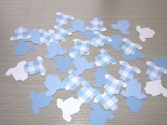 blue and white paper cutouts are scattered on a wooden surface, with one piece missing