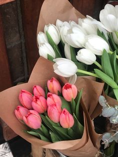 a bunch of white and pink tulips sitting on top of brown paper bags