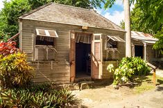 an old wooden building with shutters on the front and side windows, surrounded by trees