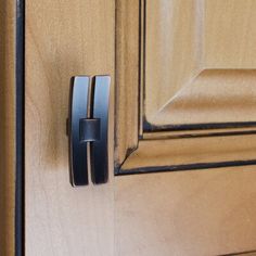 a close up of a door handle on a wooden door with black hardware and wood grained background