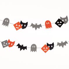 a halloween garland with black and orange paper bats, ghost heads, and faces on it