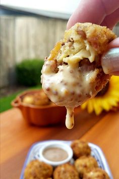 a person is holding up some food to the camera and dipping sauce on top of it