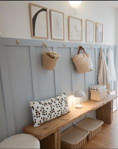 a wooden bench sitting next to a wall with baskets hanging on it's side