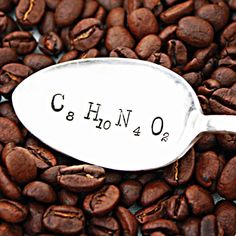 a spoon full of coffee beans with the word c and h on it