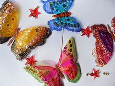 there are many different colored butterflies on the white table top, with red stars around them