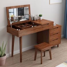 a wooden desk with a mirror and stool in the corner next to a potted plant