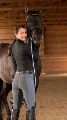 a woman standing next to a brown horse