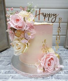 a pink and gold birthday cake with flowers on top