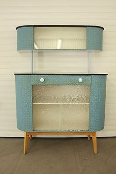 a blue and white cabinet sitting on top of a wooden floor next to a wall