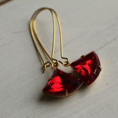 These beautiful fan shaped vintage glass jewels are a beautiful and rich shade of ruby red. The classic fan shape of the stone is reminiscent of Art Deco in its simplicity and strong lines, and the glass has been foiled with gold from behind, so it really catches the light beautifully. The jewel is hung on gold plated ear wires. These earrings are available in two different lengths, which are identical in style and appearance. The longer option is 5cm (two inches) long with the sapphire jewel ha Red Jewelry For Pierced Ears As A Gift, Ruby Drop Earrings As A Gift, Handmade Red Crystal Earrings For Gift, Elegant Handmade Red Crystal Earrings, Ruby Dangle Earrings For Party, Nickel-free Ruby Earrings As A Gift, Nickel-free Ruby Earrings For Gift, Nickel Free Ruby Earrings As A Gift, Faceted Teardrop Red Jewelry