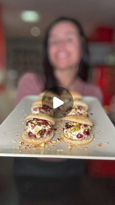 a woman holding a tray with food on it in front of her face and smiling at the camera