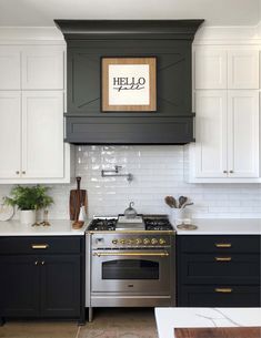 a kitchen with black and white cabinets, gold trimmings and an art print above the stove