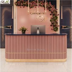 the reception desk is decorated with pink flowers and greenery, along with a laptop on it