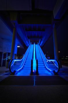 an escalator is lit up with blue lights at the bottom and on top