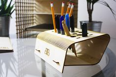 an office desk with pens and pencils in a holder on top of the desk