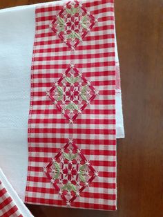 two red and white napkins on top of each other with green flowers in the middle