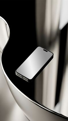 a cell phone sitting on top of a white table next to a metal object with curved edges