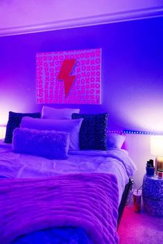 a bedroom with purple lighting and a large painting on the wall above the headboard