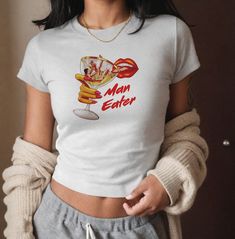 The Man-Eater baby is here!  Not to be confused with the modern-day crop top, the '90s-era baby tee is a shrunken-down T-shirt, born out of the 90s skater/raver culture era. Available in white or black: The shoulders have twill tape for improved durability. The collar is curl resistant due to ribbed knitting. There are no seams along the sides.  .: Made with 100%, mid-weight, US cotton that feels soft to the touch and a great choice for any season. .: The crew neckline along with the tee's class 90s Style Cropped T-shirt For Spring, Y2k Funny Print Crop Top For Streetwear, Y2k Funny Print Short Sleeve Crop Top, Y2k Style Funny Print Short Sleeve Crop Top, Y2k Short Sleeve Crop Top With Funny Print, Y2k Graphic Print Cropped T-shirt, 90s Style Crop Top T-shirt For Spring, 90s Style Spring Crop Top T-shirt, Retro Fitted Crop Top T-shirt