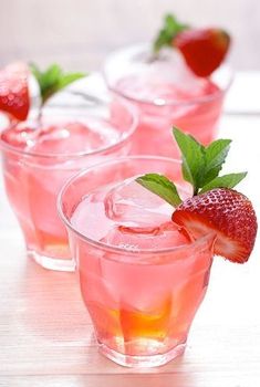 three glasses filled with pink lemonade and strawberries