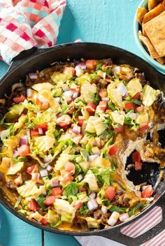 a mexican dish with tortilla chips and salsa in a skillet on a blue table