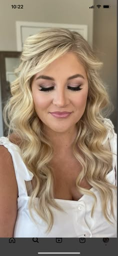 a woman with long blonde hair wearing a white dress and makeup looks at the camera