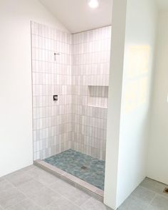 an empty bathroom with tiled walls and floor, including a walk in shower next to a white wall