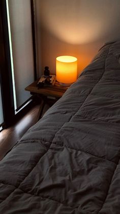 a bed sitting next to a window with a lamp on top of it in a bedroom