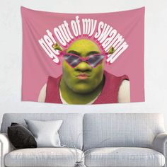 a couch with a pink wall hanging above it and the words let's out of my swamp